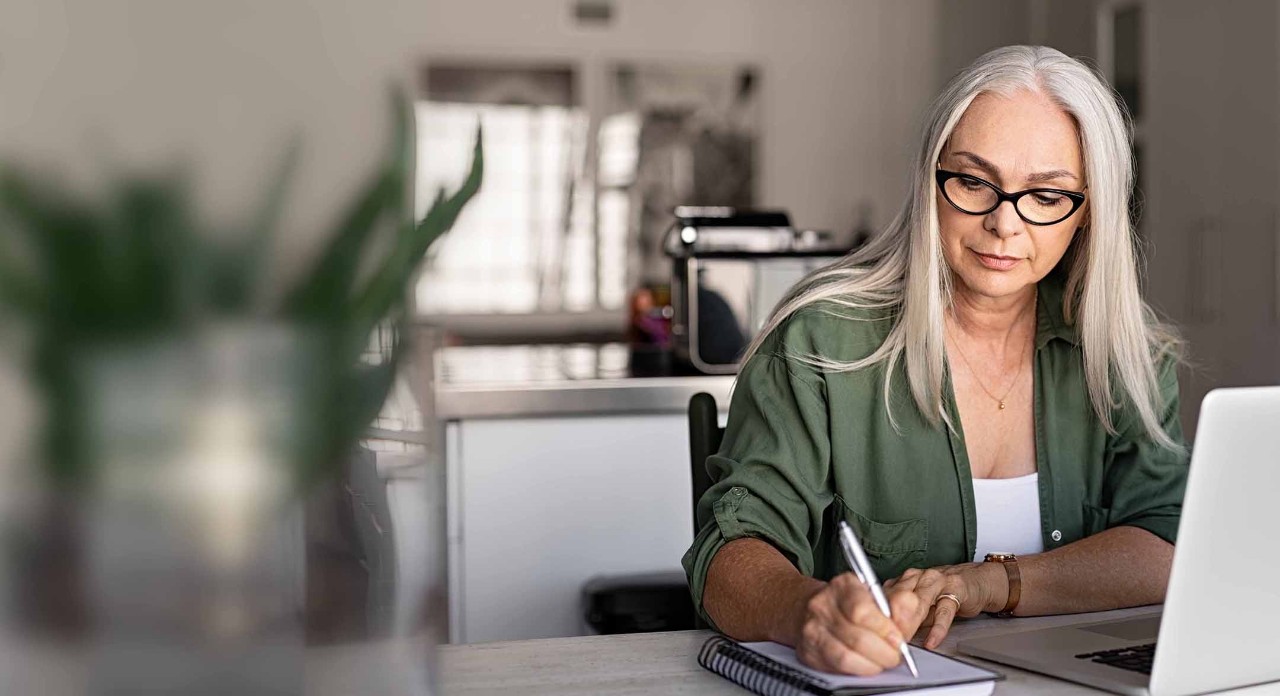 Lady sat at a table and making notes on her notepad