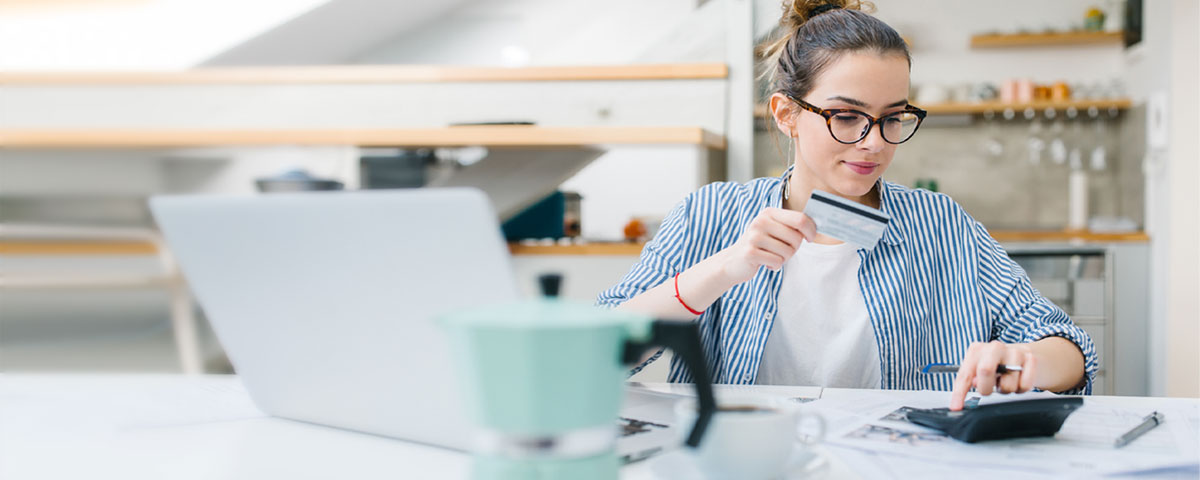 A woman at a desk holding a credit card