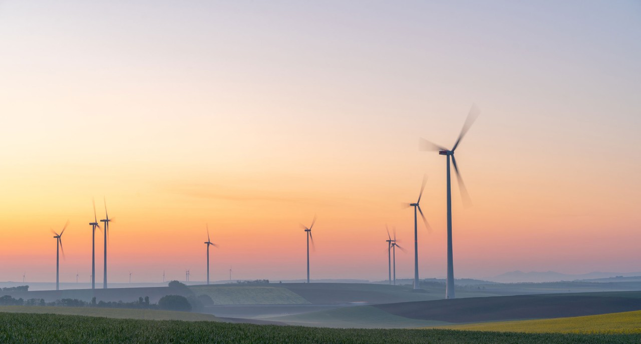 Photo of a wind turbine in front of a misty sunrise