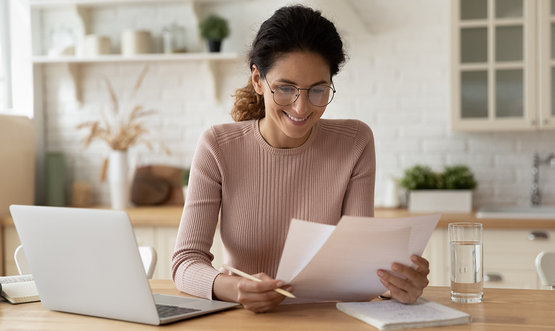 Person working at a desk with a laptop and documents.
