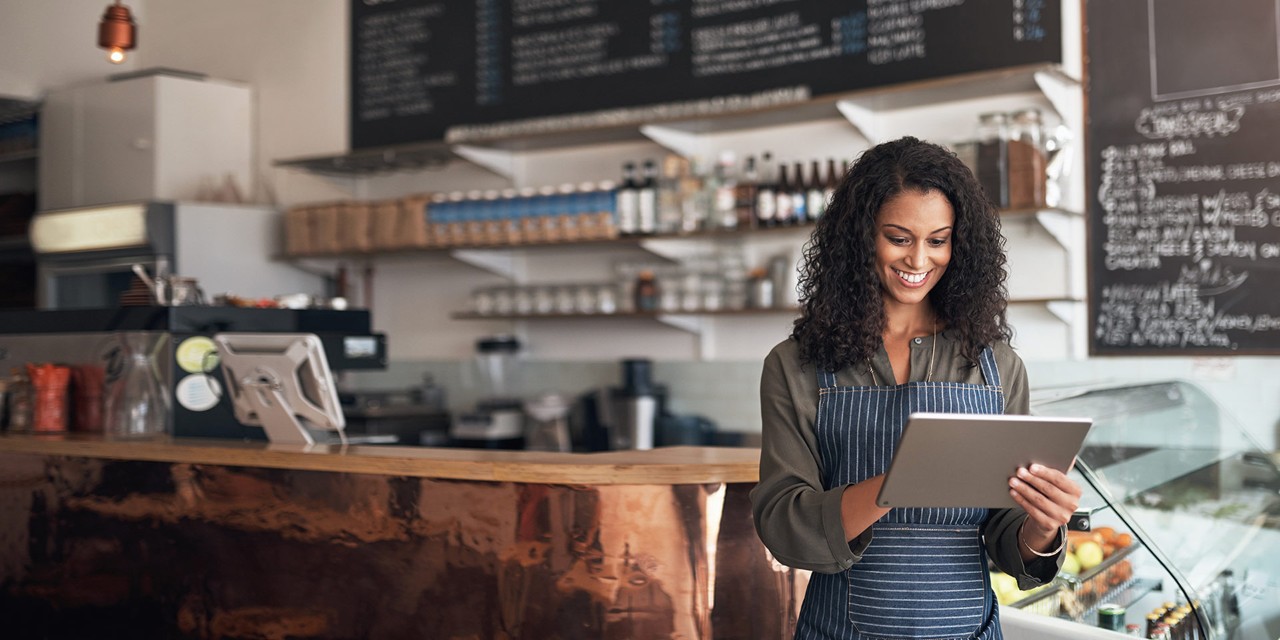 Person standing in a café using a tablet.