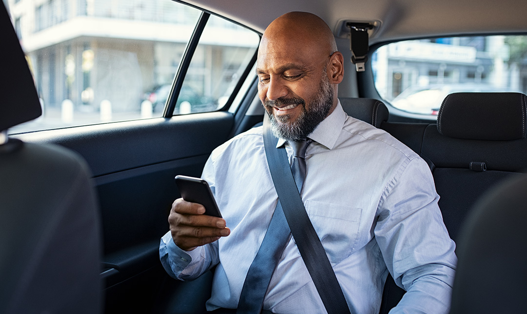 Person using a phone in the back seat of a car.