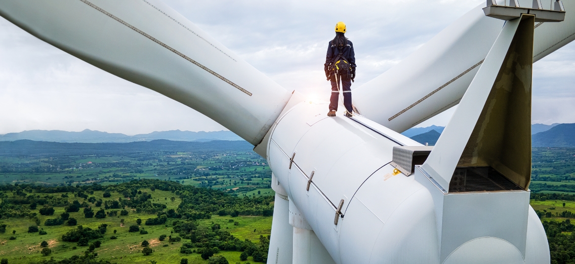A female worker standing on top of a wind turbine looking out to the fields
