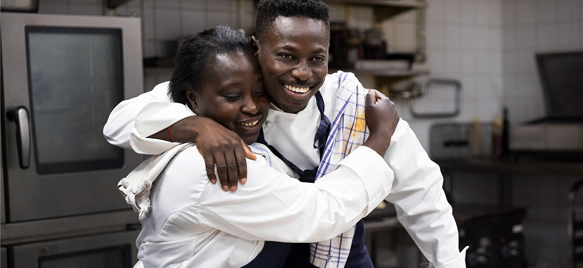 Photo of male and female chefs hugging in kitchen