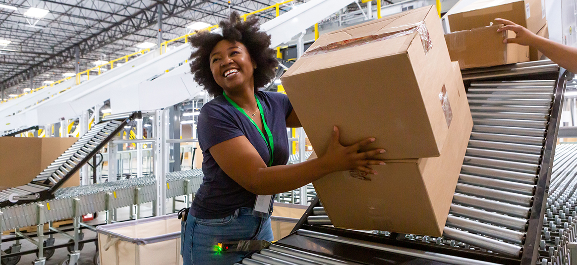 Smiling female worker in a warehouse moving boxes