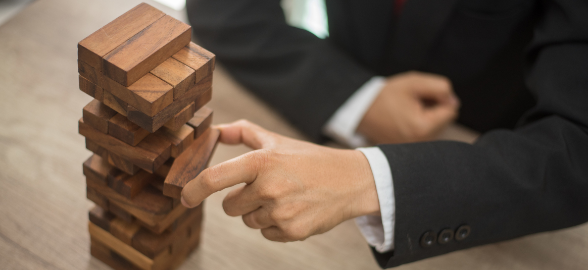 Photo of a suited person pulling out a block from a Jenga tower