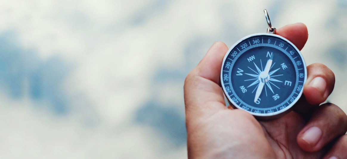 Photo of a compass pointing north on a blurred blue background