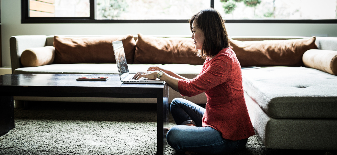 Photo of a woman sitting at a coffee table working at a laptop