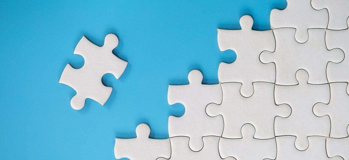 Partially assembled white jigsaw on a light blue background