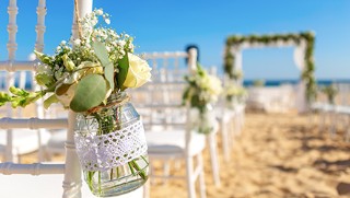 Jar with flowers on a chair as wedding decor, placed on the beach as the venue. 
