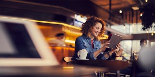 Woman drinking a coffee looking at tablet