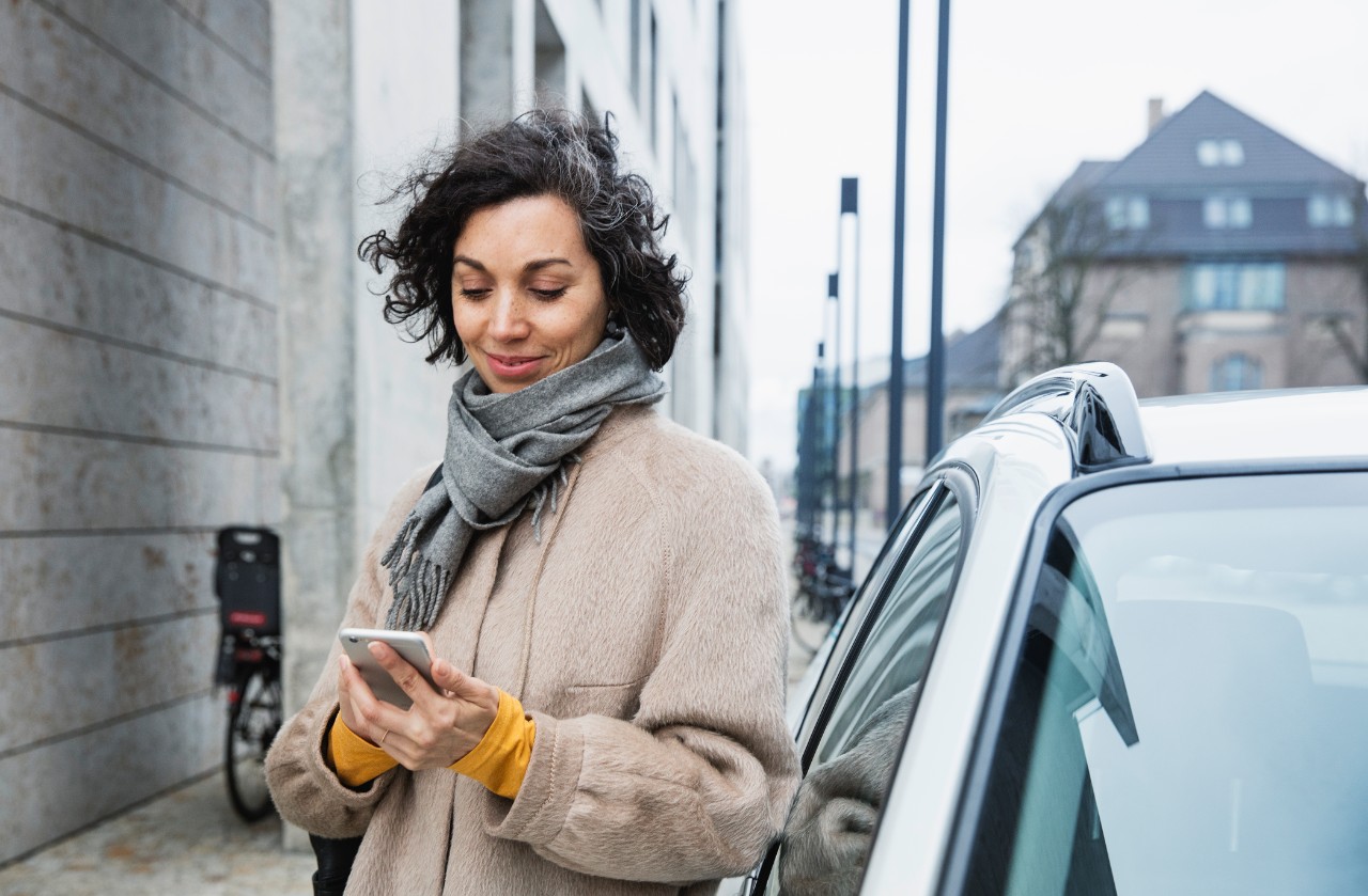 Woman next to car looking at phone