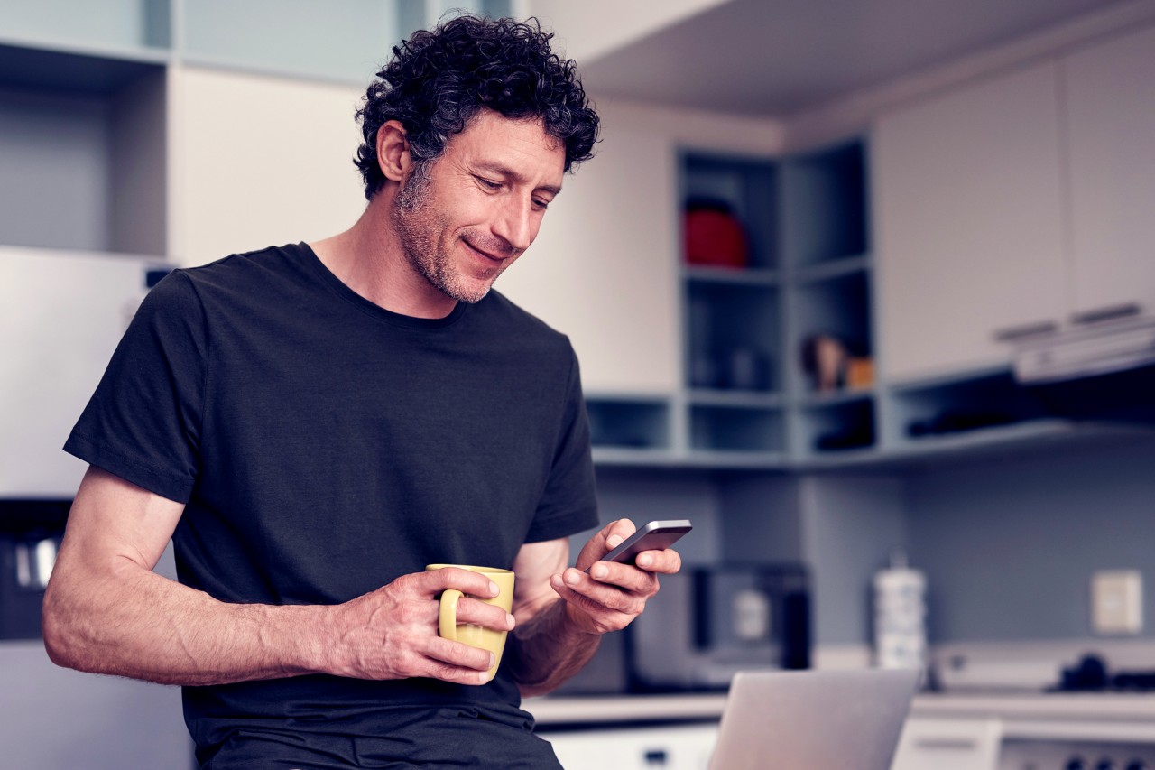 Man using phone in kitchen