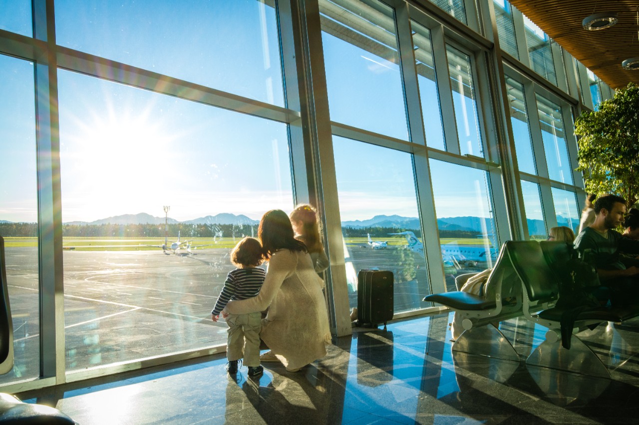 Woman with children looking out at the runway at airport